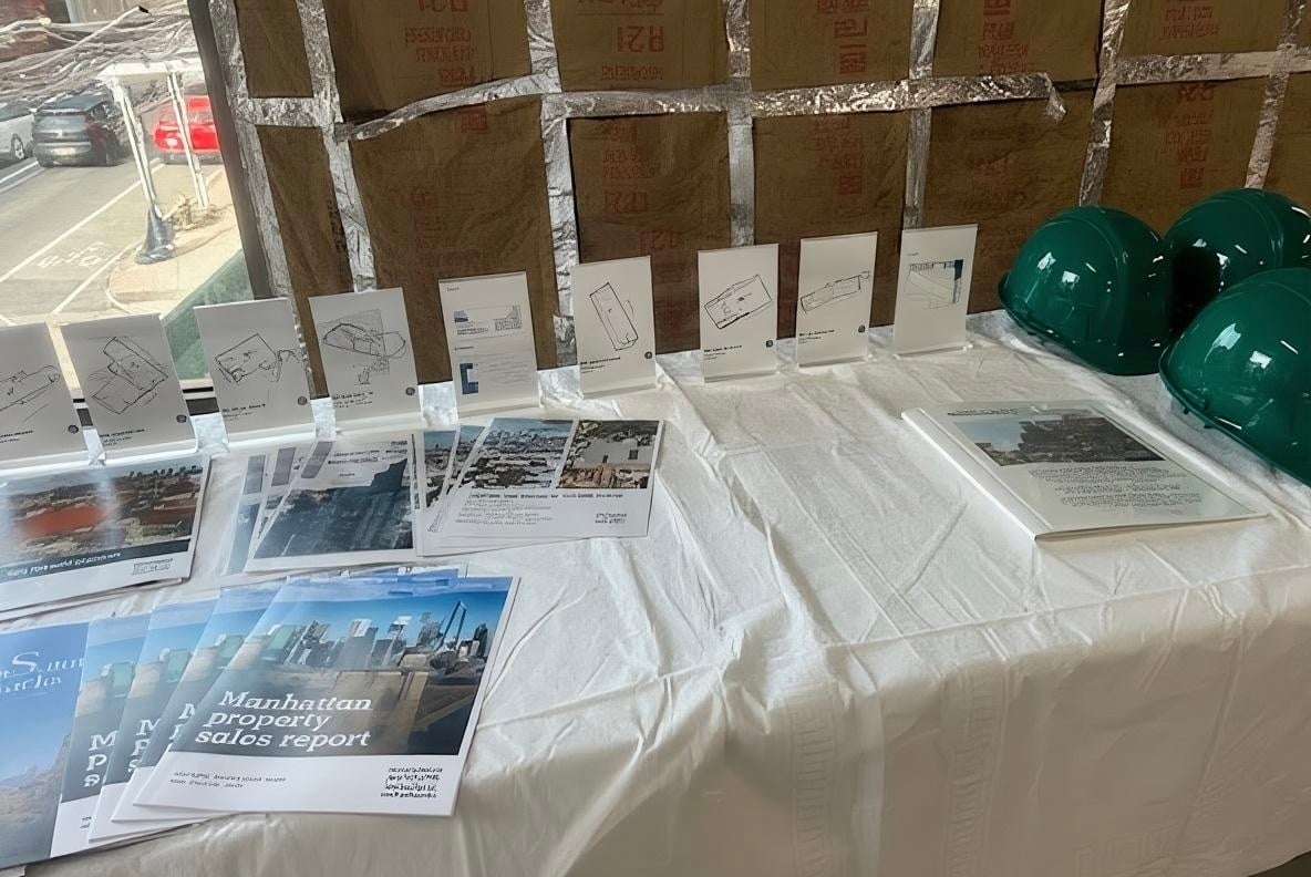 Table with property brochures, floor plans, and safety gear prepared for attendees at the REBNY Brooklyn Commercial Committee Gowanus event.