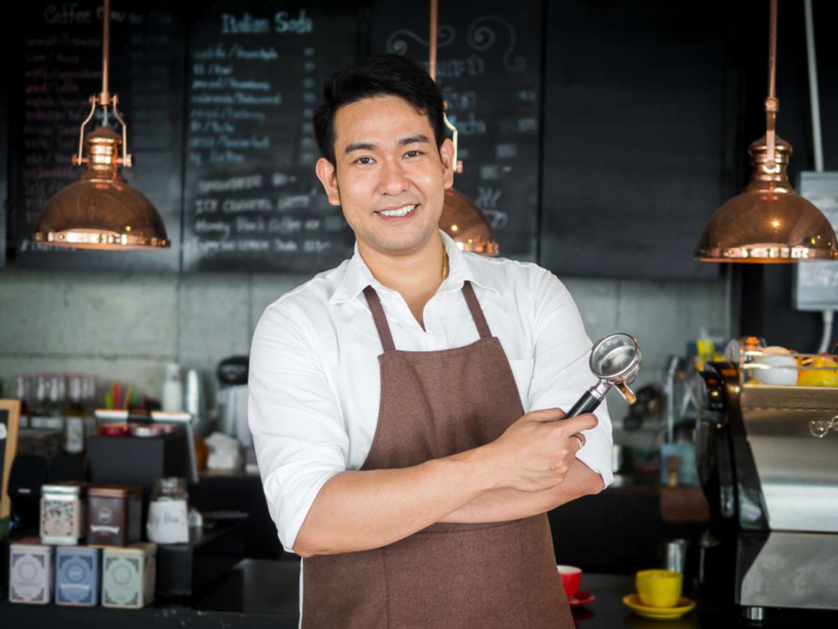 Asian barista man standing in front of bar with crossed arm, lifestyle concept
