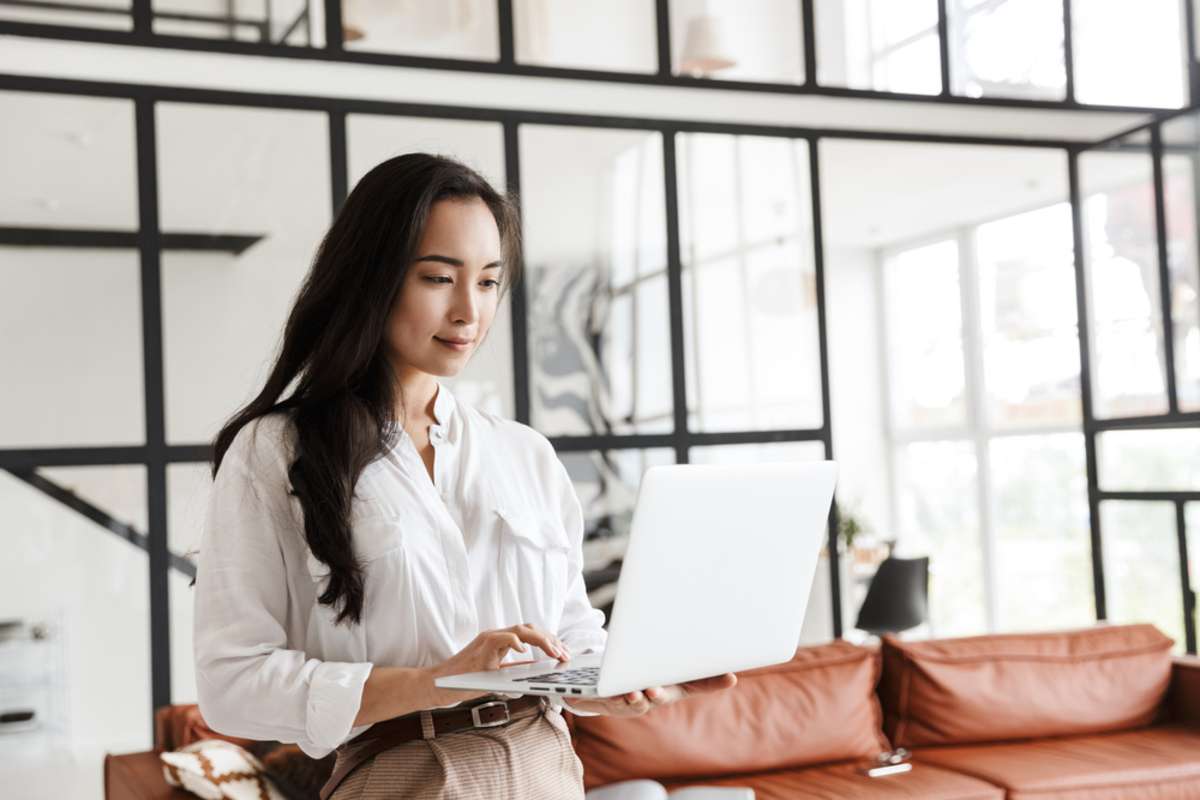 Attractive young brunette asian woman using laptop computer while standing