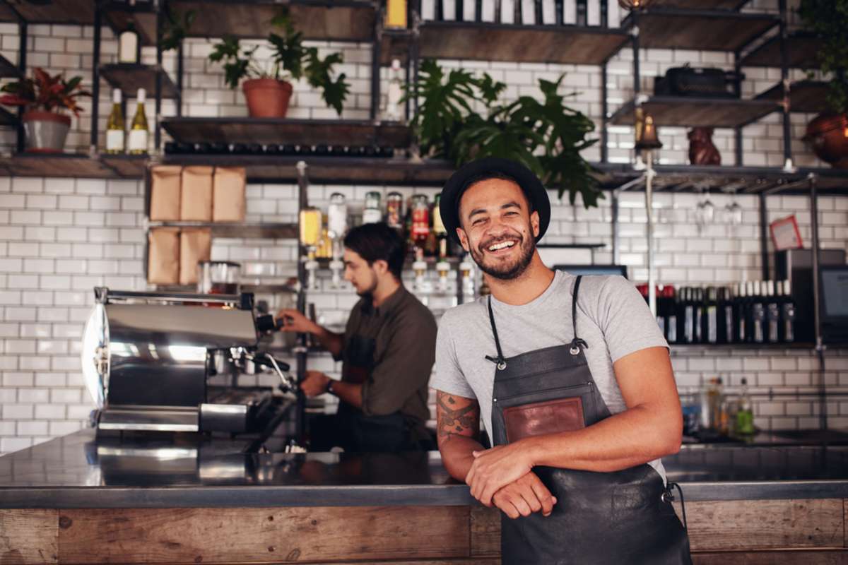 Coffee shop worker smiling to camera, standing at the counter
