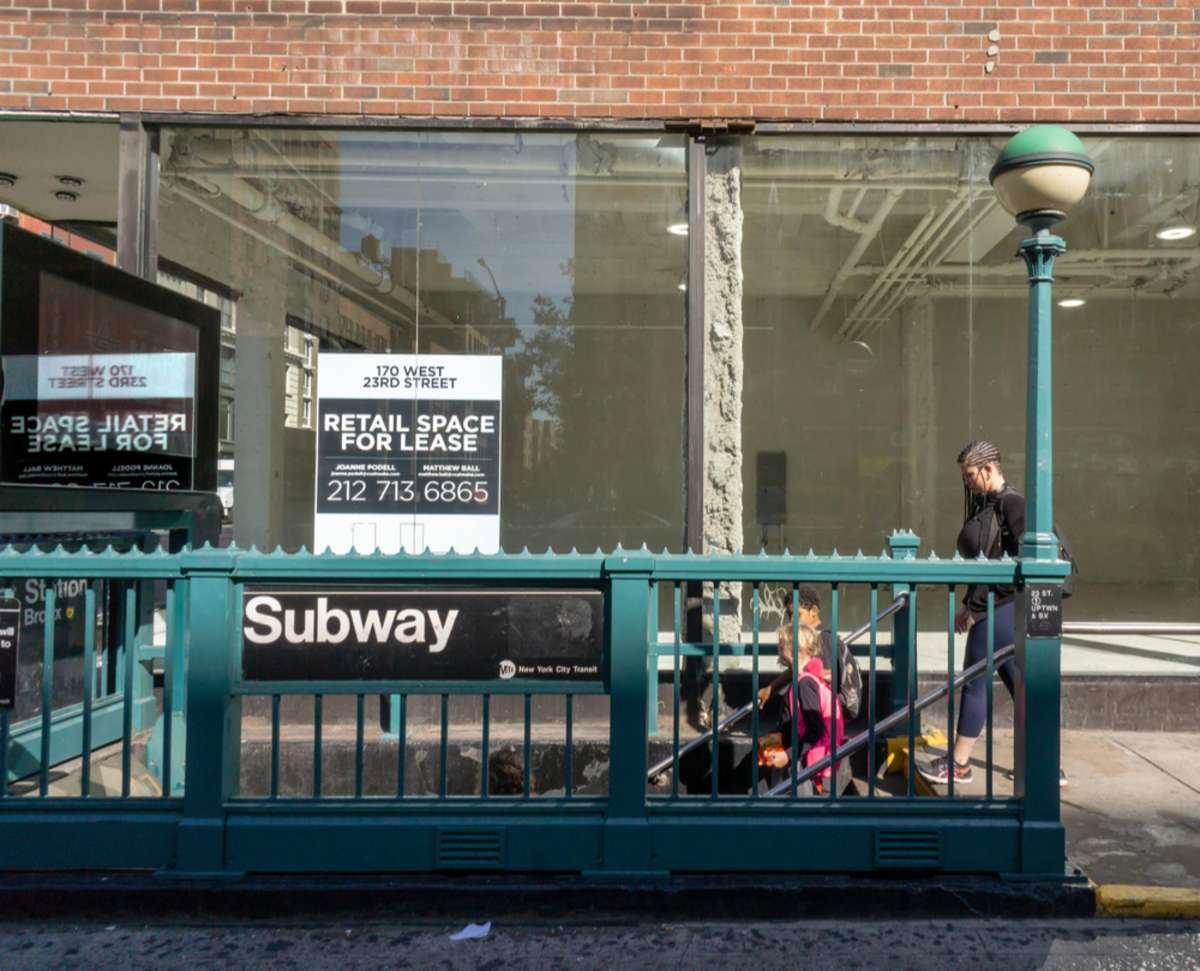 Commuters enter the subway in front of retail space