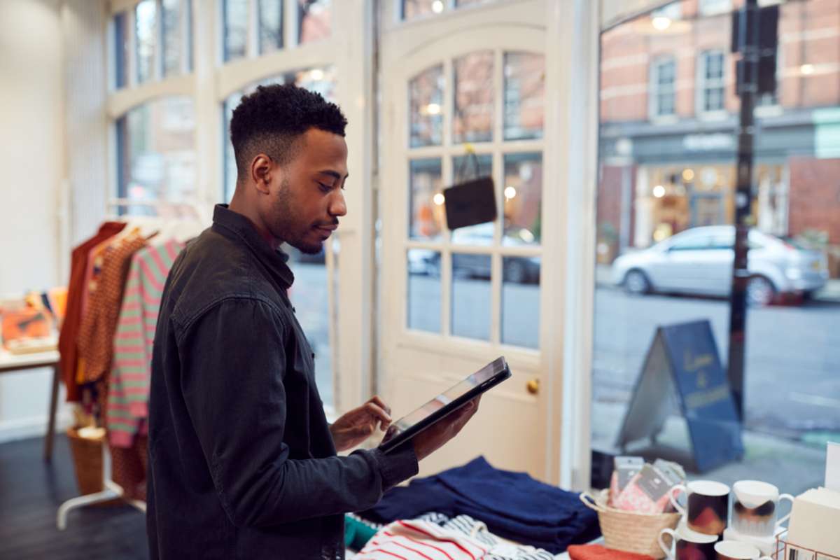 Male Small Business Owner Checks Stock In Shop Using Digital Tablet