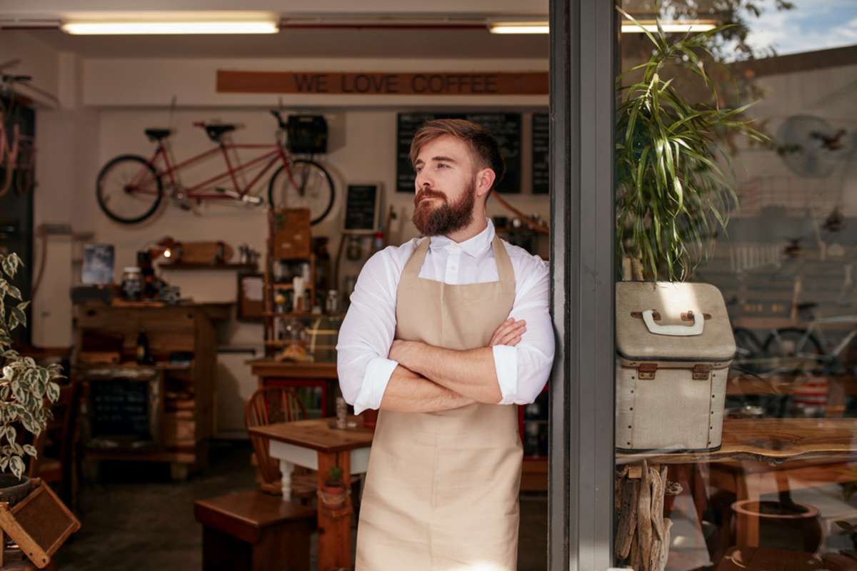 Portrait of a cafe owner standing in the doorway of his coffee shop