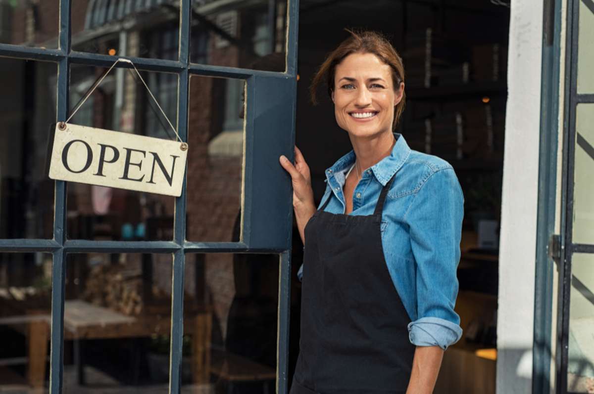Portrait of a happy waitress standing at restaurant entrance