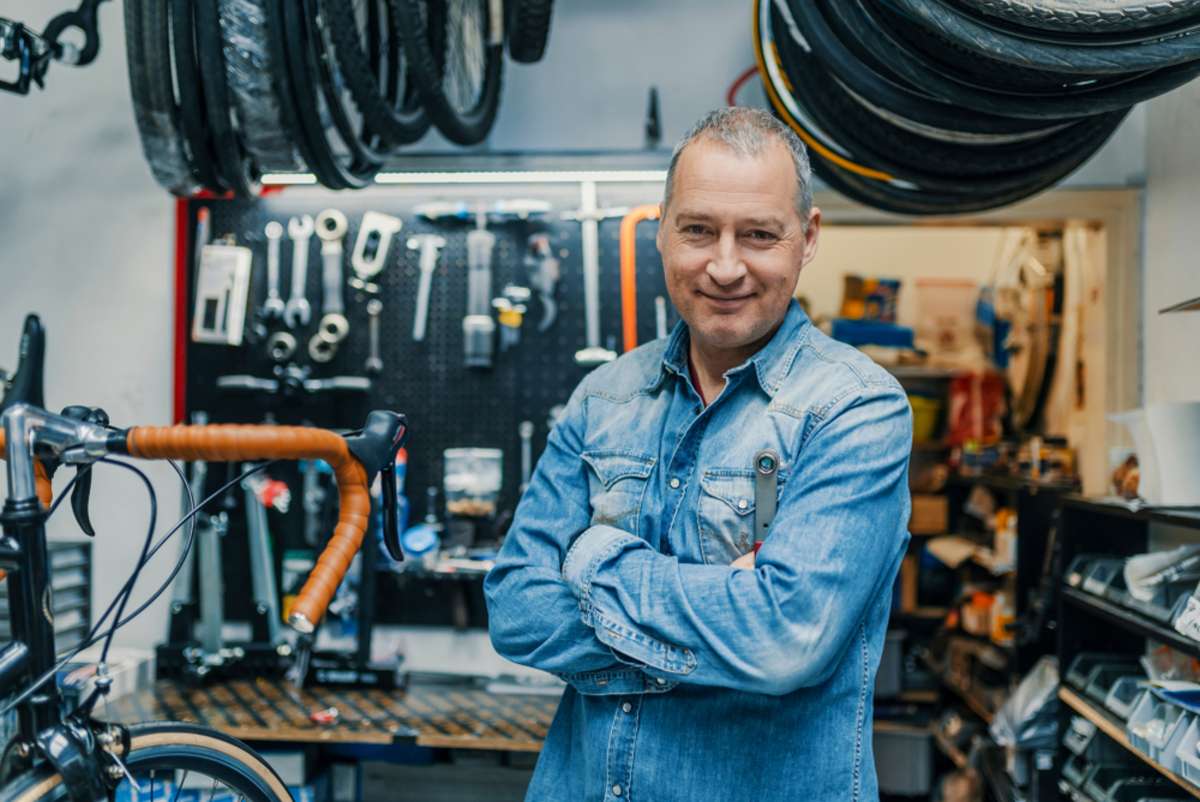 Stylish bicycle mechanic standing in his workshop