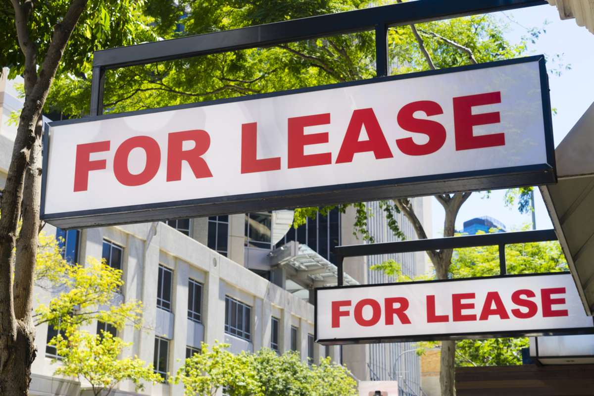 Two For Lease signs on display outside buildings during daytime