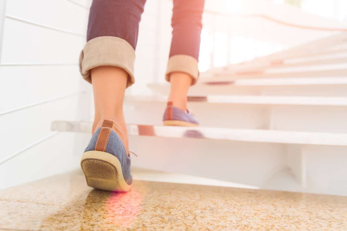 Young adult woman walking up the stairs with sun sport background