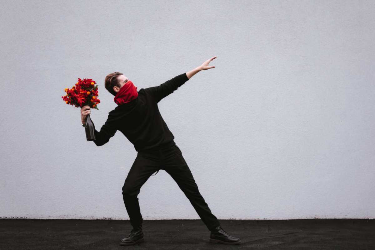 Young man in black clothes throwing red bouquet