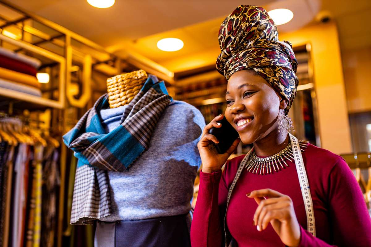 tanzanian woman with snake print turban over hear working in fabrics shop